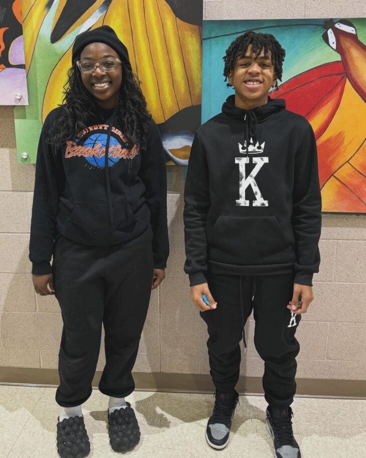  two students posing in front of butterfly pictures